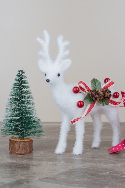 Pine tree and toy deer on marble table.