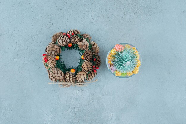 Pine wreath and a candy holder with noguls and a tree figurine on marble.