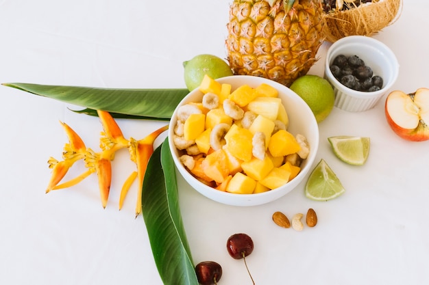 Pineapple; banana and apple salad in white bowl with lemons