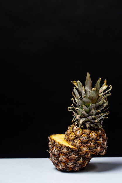 Free photo pineapple cut in half on a table on a black