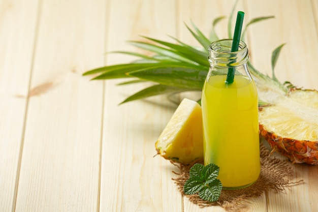 Pineapple juice in bottle on wooden surface