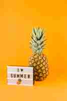 Free photo pineapple near the light box with word i love summer against yellow backdrop