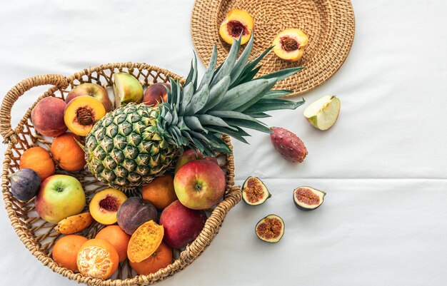 Pineapple and other exotic fruits in a basket on a white background top view