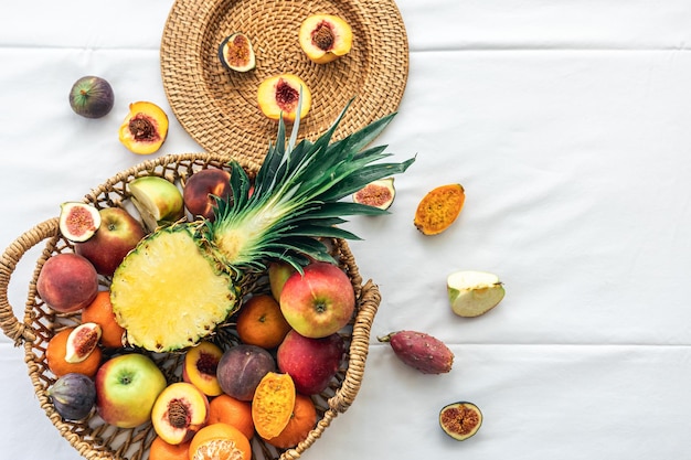 Pineapple and other exotic fruits in a basket on a white background top view