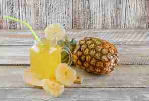 Free photo pineapple with candied rings, juice on wooden surface