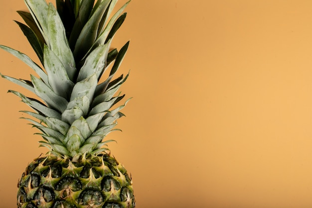 Pineapple with green leaves on a orange color wall