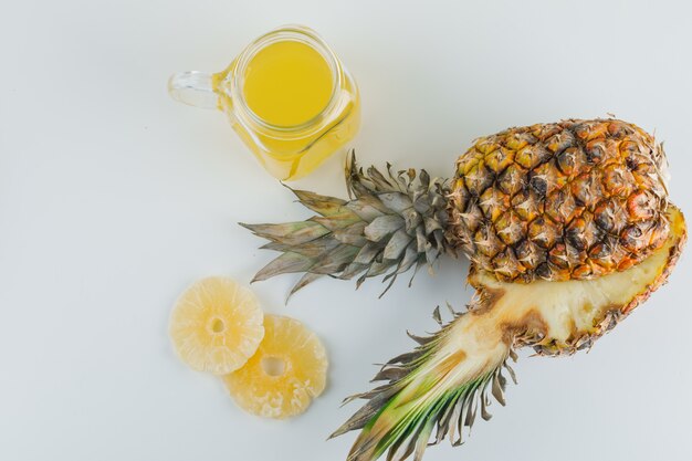 Pineapple with juice and candied rings on white surface