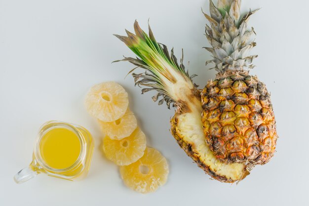 Pineapple with juice and candied rings on white surface