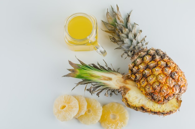 Pineapple with juice and candied rings on white surface
