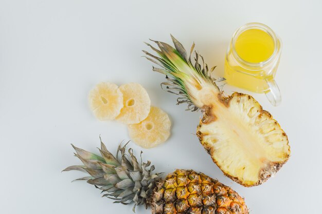 Pineapple with juice and candied rings on white surface