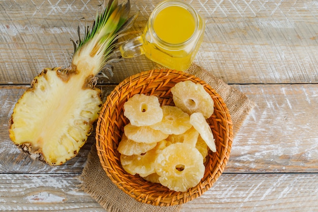 Pineapple with juice and candied rings on wooden surface