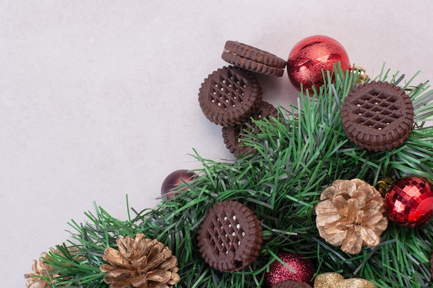 Pinecones with Christmas balls and cookie on white surface