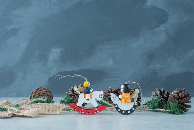 Free photo pinecones with small christmas festive toys on marble background. high quality photo