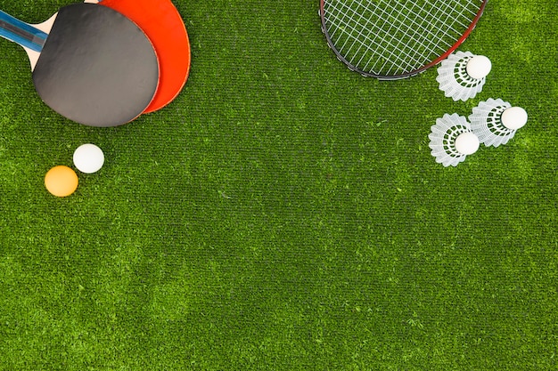 Ping-pong balls; shuttlecock; badminton and rackets on green turf