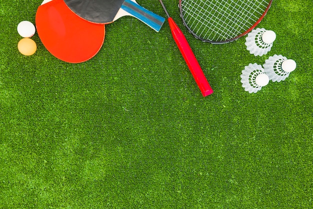 Free photo ping-pong balls; shuttlecocks; badminton and rackets on green turf