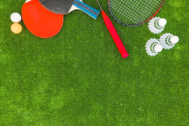 Ping-pong balls; shuttlecocks; badminton and rackets on green turf