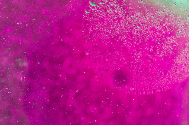 水に浮かぶ油泡とピンクの抽象的な背景