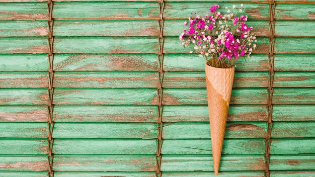 Pink baby's-breath flowers inside the waffle cone against wooden shutters