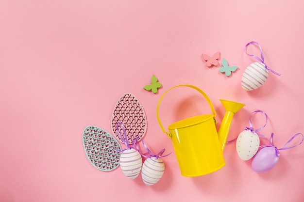 Free photo pink background with easter eggs and yellow watering can