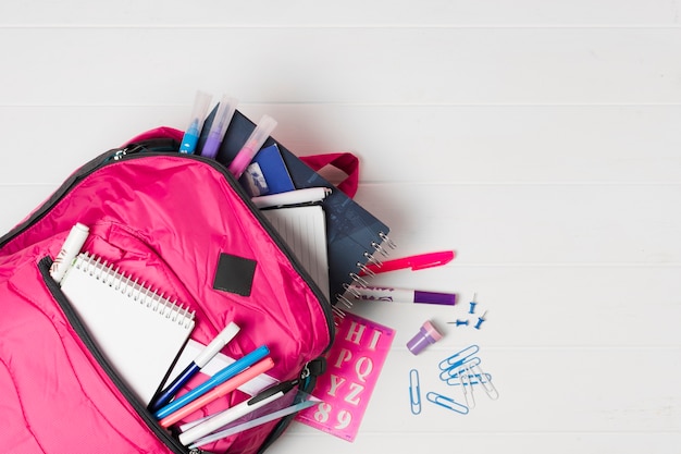 Pink backpack with school supplies top view 