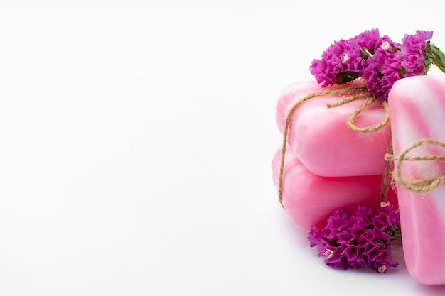 Pink bars of handmade natural soap and flowers isolated on white