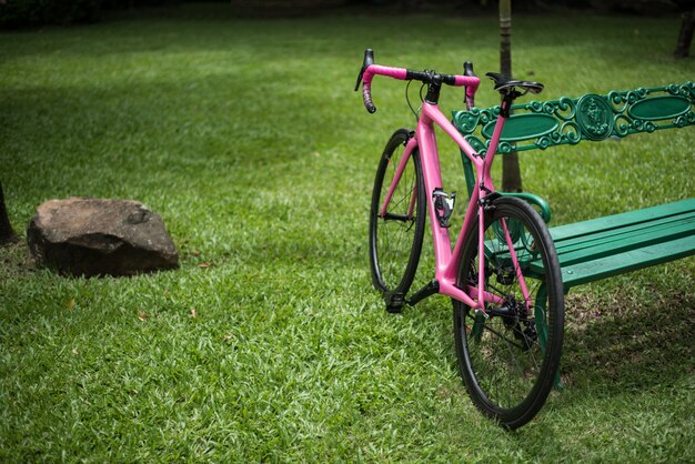 公園のベンチに傾いているピンクの自転車