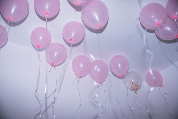 Free photo pink birthday balloons with streamers touching the ceiling