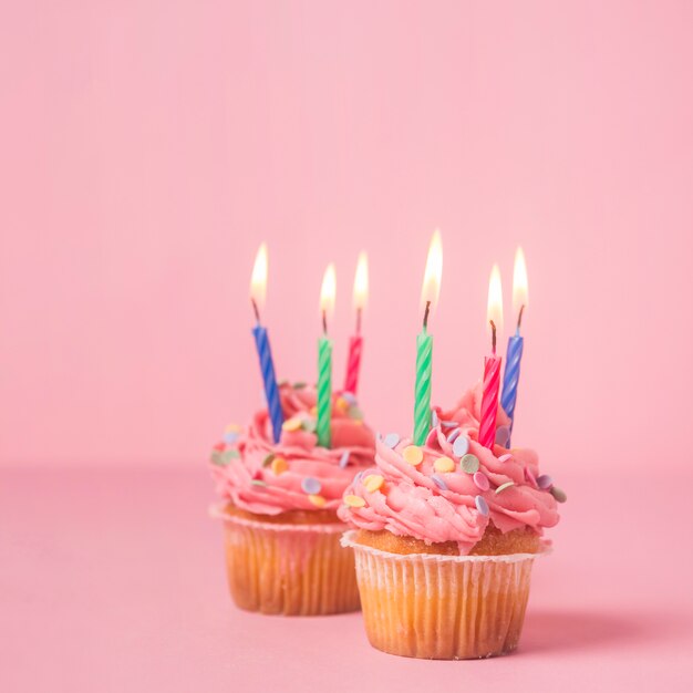 Pink birthday cupcake wit lit candles