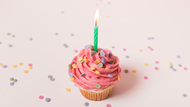 Pink birthday cupcake with lit candle