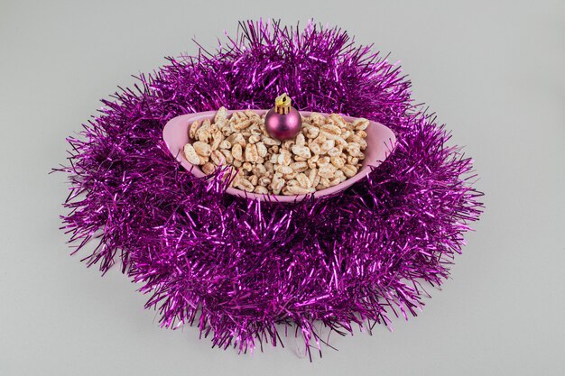 A pink bowl full of healthy cereals with Christmas balls .