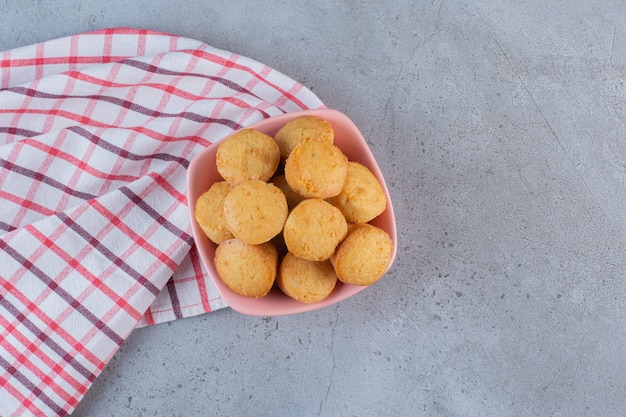 Free photo pink bowl of mini sweet cakes on stone background.