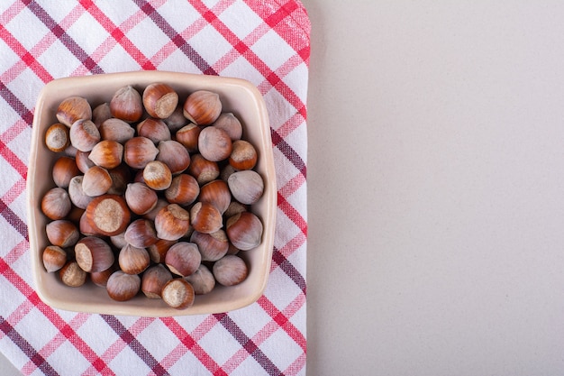 pink bowl of shelled organic hazelnuts placed on white background. high quality photo
