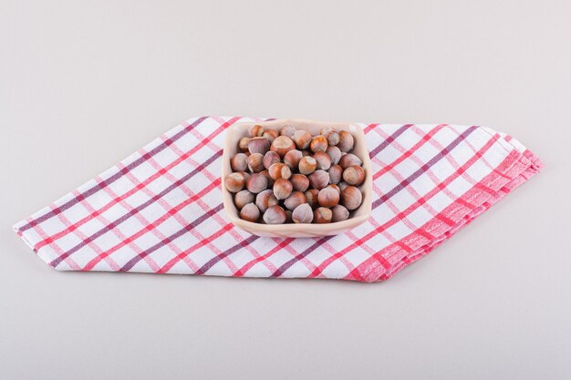 Pink bowl of shelled organic hazelnuts placed on white background. High quality photo