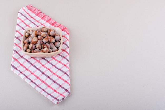 Pink bowl of shelled organic hazelnuts placed on white background. High quality photo