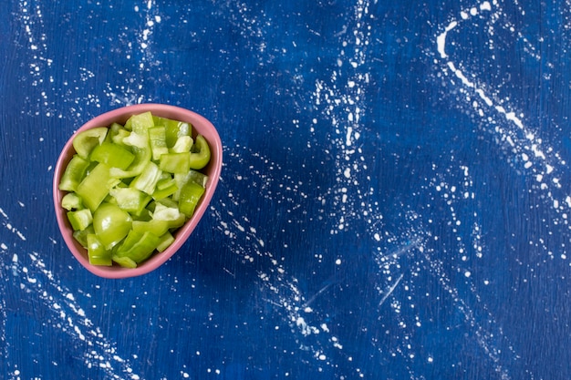 Free photo pink bowl of sliced green bell peppers on marble surface