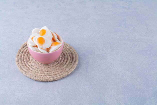 A pink bowl with sweet jelly-fried eggs on gray table . 
