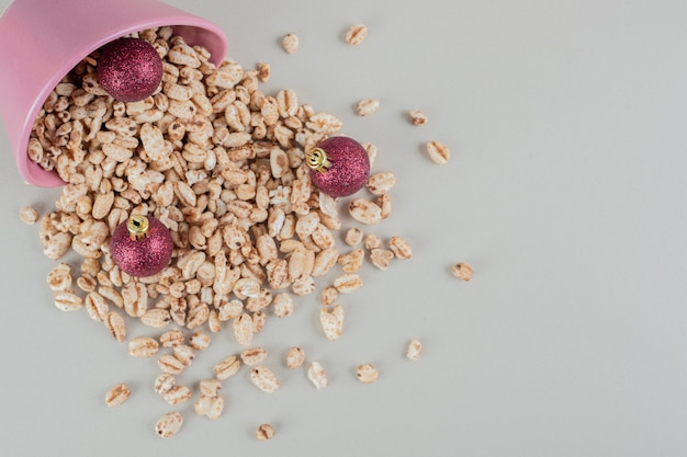 A pink bucket full of healthy cereals with Christmas balls .