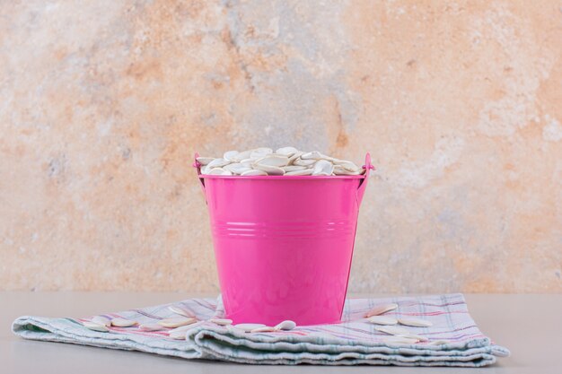 Free photo pink bucket full of organic pumpkin seeds