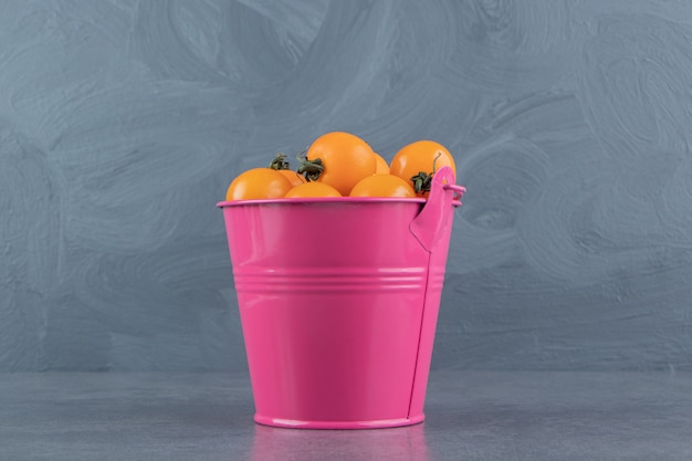 Free photo a pink bucket full of ripe tasty yellow cherry tomato