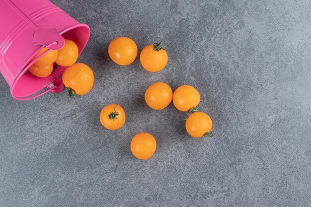 A pink bucket full of ripe tasty yellow cherry tomato 