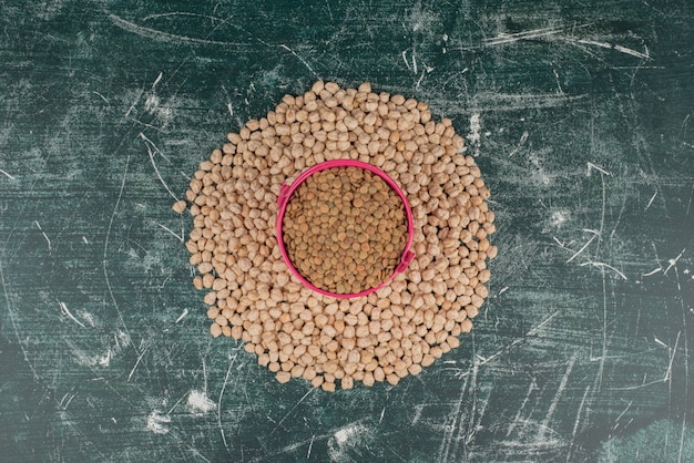 Free photo pink bucket of seeds on circle of peas on marble surface .