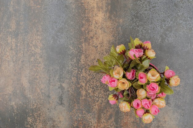 A pink bucket with bouquet of flowers on marble surface. 