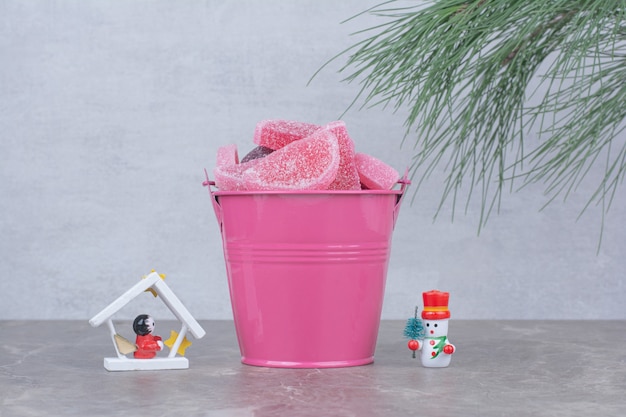 Pink bucket with sugar marmalade on marble background.