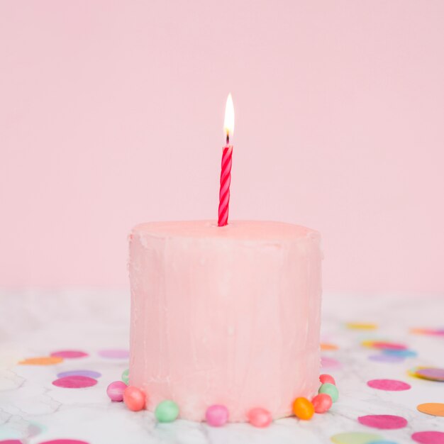 Розовый торт с освещенной свечой
