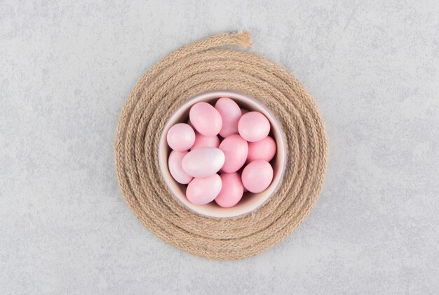 Pink candies in the cup on the trivet on the marble surface