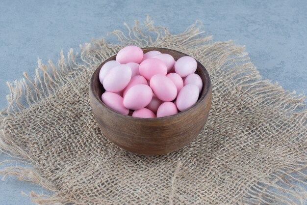 Pink candies in the cup on the trivet, on the marble table. 