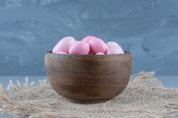 Pink candies in the cup on the trivet, on the marble table. 