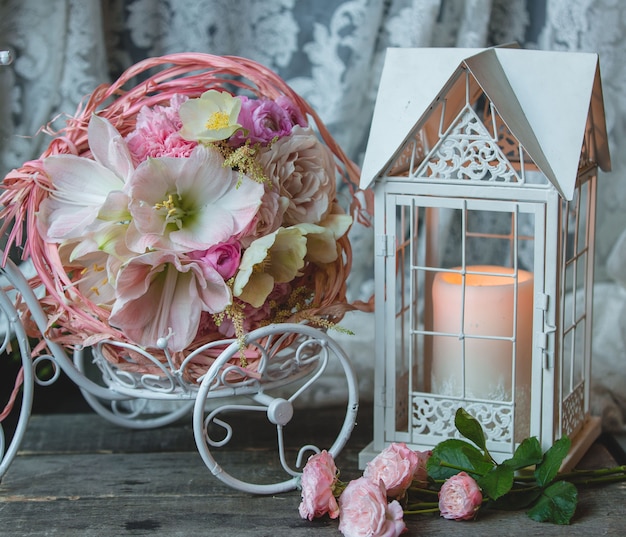 Pink candle in a fake cage, small wreath of flowers.