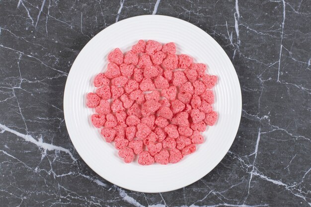 Pink cereal flakes on white plate.