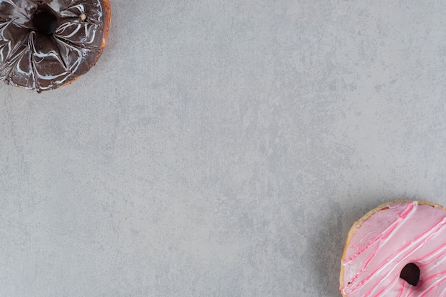 Pink and chocolate doughnuts on a concrete surface